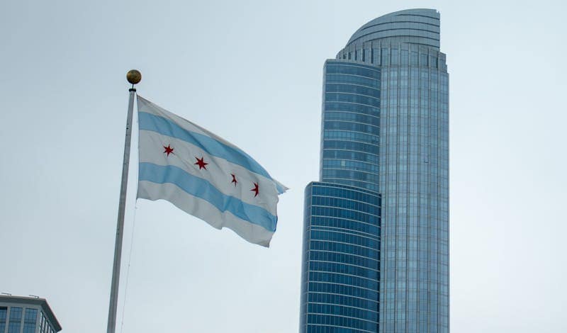 Chicago flag waving in front of a modern skyscraper on a clear day.